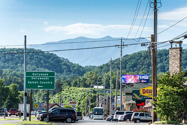 Dollywood Sign in Pigeon Forge Pigeon Forge, USA - June 16, 2016: A road sign for Dollywood amusement park in Pigeon Forge, Tennessee. Cars parked outside other businesses on the right. Various signs. tennessee road sign stock pictures, royalty-free photos & images