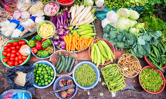 Fresh Vietnamese vegetables, fruits, and spices displayed at  an improvised Hanoi street market on a sidewalk. Each ingredient is in a bowl or basket.
