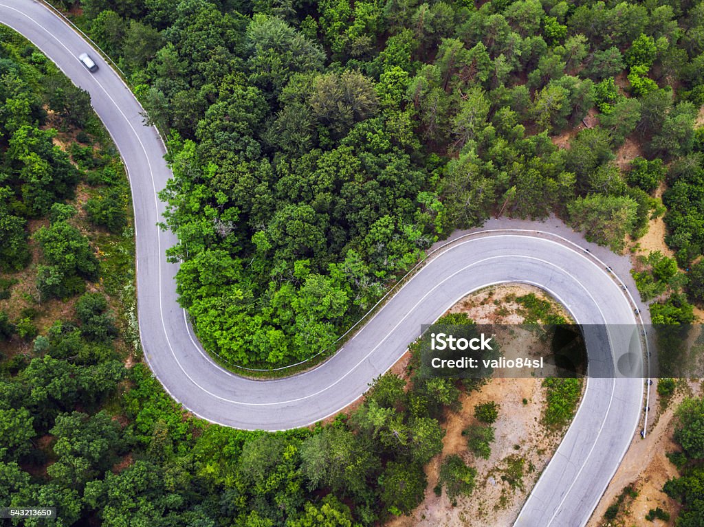 Aerial view over mountain road Aerial view over mountain road going through forest landscape Aerial View Stock Photo