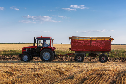 Red tractor with red trailer ina field