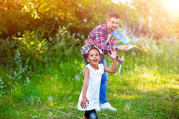 istock Happy father and daughter playing soap bubbles in park. 543214920