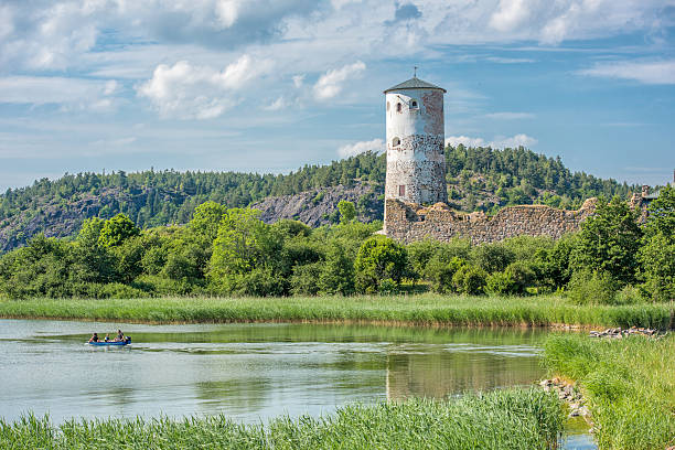 Stegeborg Castle during midsummer in Sweden Stegeborg, Sweden - June 25, 2016: People in a small leisure boat in the bay of Slatbaken pass the ruin of Stegeborg castle during midsummer in Sweden. Stegeborg is a historic medieval royal castle ostergotland stock pictures, royalty-free photos & images