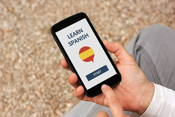 hands holding smart phone with learn spanish concept on screen - spanish culture teacher learning text imagens e fotografias de stock
