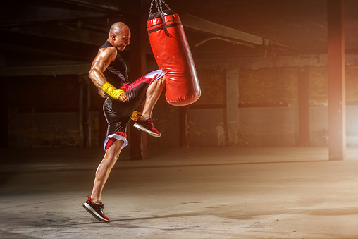 MMA fighter practicing knee kick to punching bag