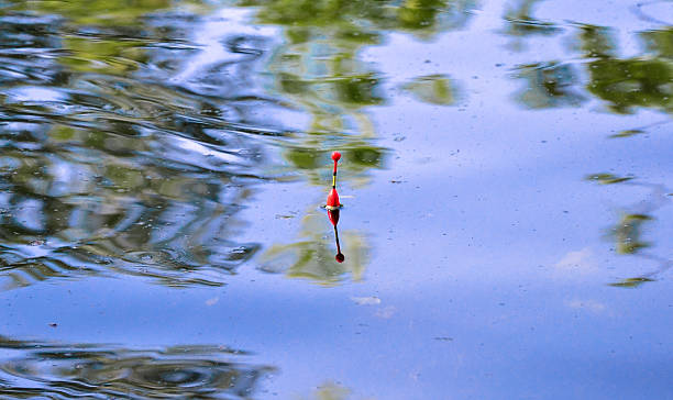 istock Red fishing float in blue river 543220258