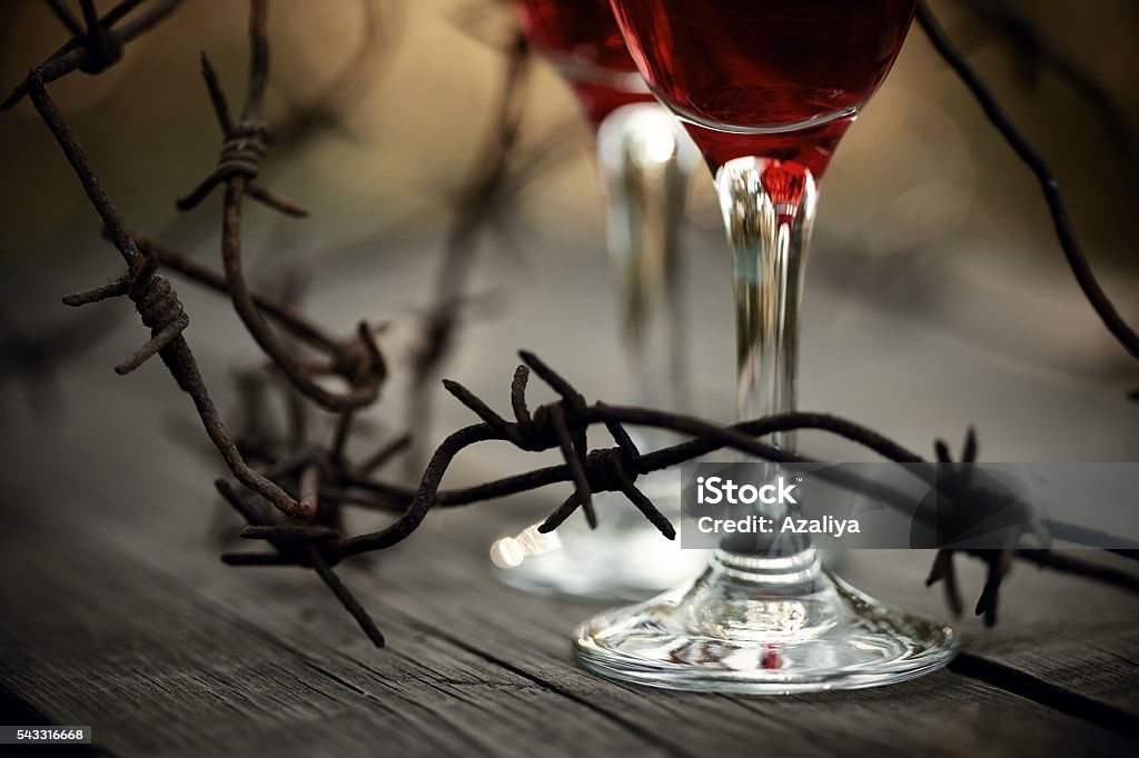 Rusty barbed wire and glasses with red wine. Rusty barbed wire and glasses with red wine on a table.  Alcoholic dependence. Abuse Stock Photo
