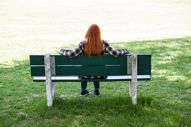 istock Young woman sitting alone on park bench. 543318010