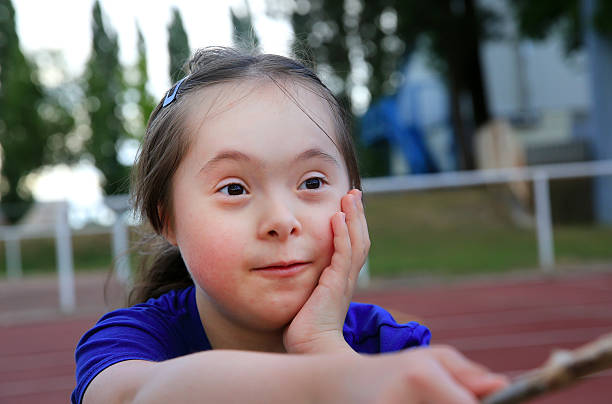 petite fille s'amuser sur le stade - child cheerful little girls down syndrome photos et images de collection