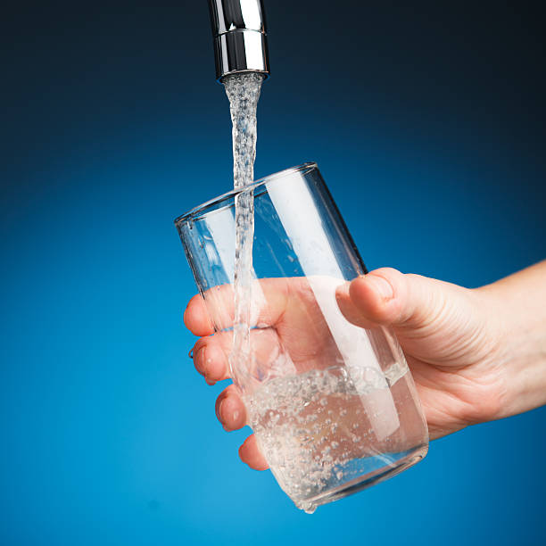 istock hand pouring a glass of water from filter tap 543321942
