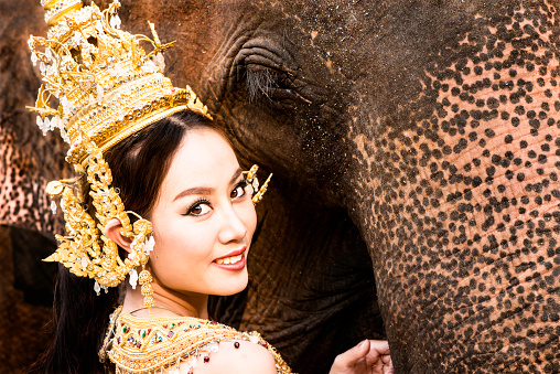 Tradtionally dressed Thai model close up with an elephant.
