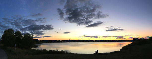A girl standing by the shore of a lake in summer sunlight.