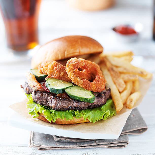 bacon barbecue burger topped with onion rings on white table