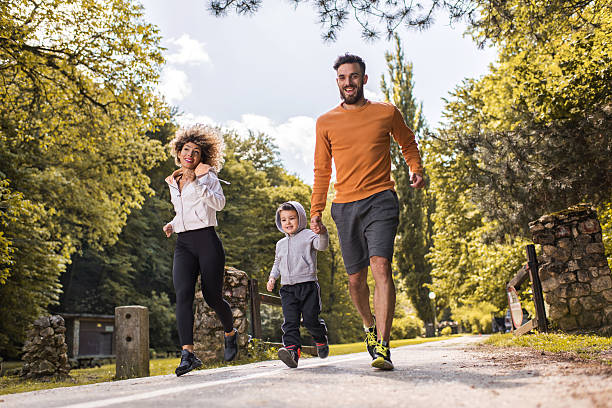 familia feliz divirtiéndose mientras corriendo en el parque. - family sport exercising jogging fotografías e imágenes de stock