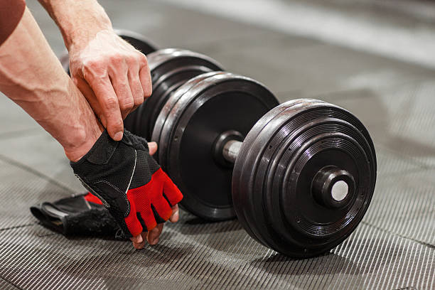 homem colocou luvas esportivas antes de flexionar halteres - flexing muscles men human muscle human arm - fotografias e filmes do acervo