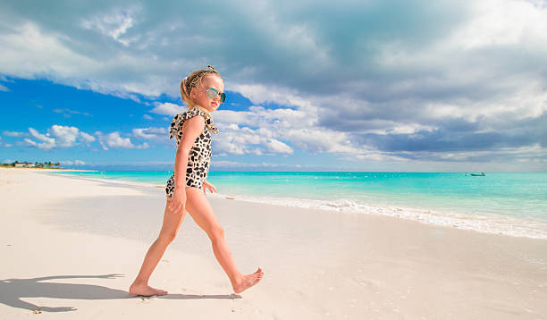 Adorable little girl at shallow water on the beach Cute little girl at beach during summer vacation turks and caicos islands caicos islands bahamas island stock pictures, royalty-free photos & images