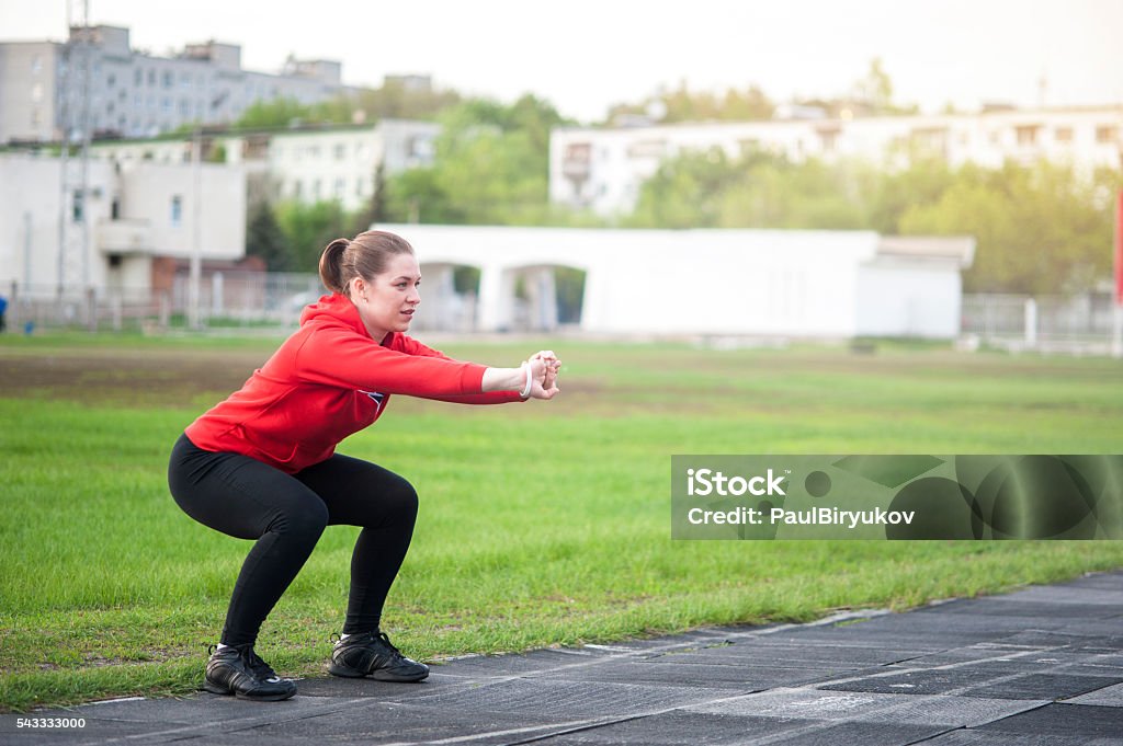 Frau im sportbekleidung im Freien squats arbeitet - Lizenzfrei Aktiver Lebensstil Stock-Foto