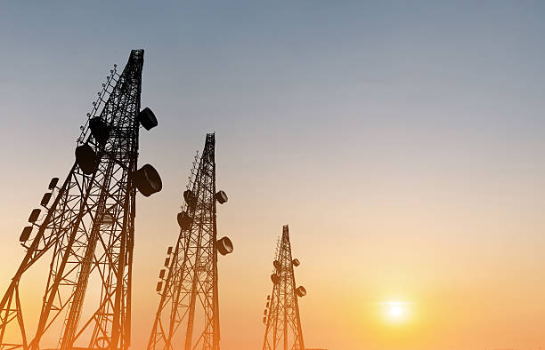 Silhouette, telecommunication towers with TV antennas, satellite dish in sunset stock photo