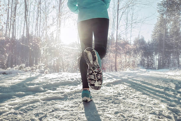 Woman Running at snowly winter under sunlight.