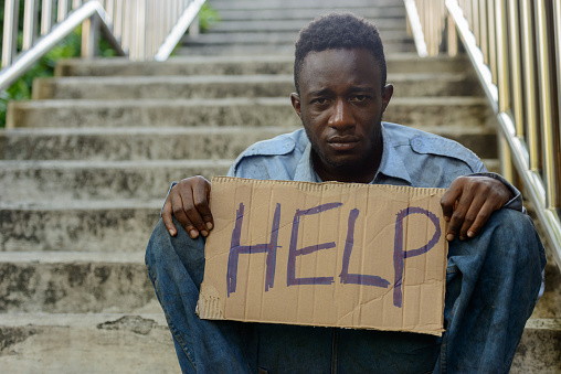 Homeless African man begging and holding HELP sign outdoors