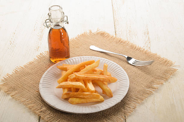 batatas fritas em uma placa de papel e vinagre de malte - foto de acervo