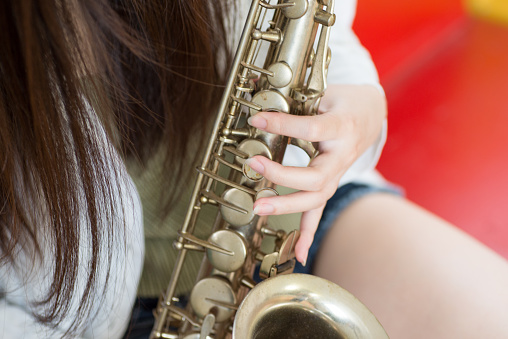 Beautiful Young Japanese Woman is practicing a saxophone