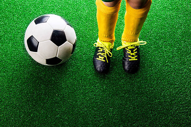 istock Unrecognizable little football player against green grass, studi 543344832