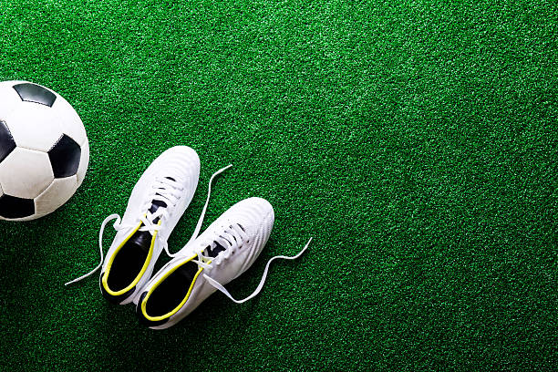 istock Soccer ball and cleats against green artificial turf, studio sho 543345198