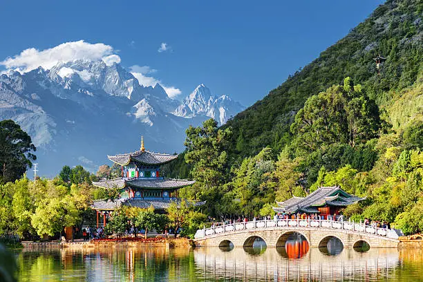 Amazing view of the Jade Dragon Snow Mountain and the Suocui Bridge over the Black Dragon Pool in the Jade Spring Park, Lijiang, Yunnan province, China.