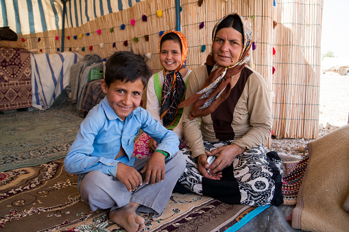 Shiraz, Iran - July 31, 2014: Iraninan nomad family, grandmother with two grandchild sitting inside their tent