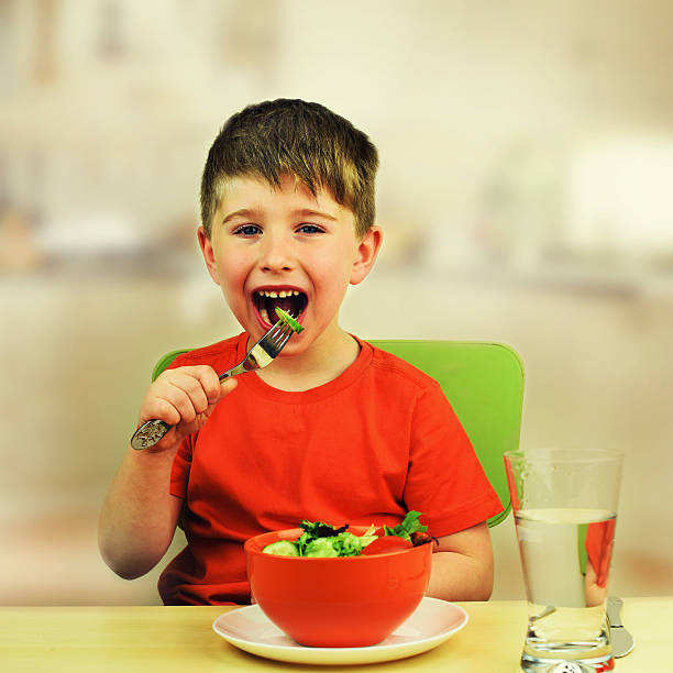 istock The little boy eats fresh salad on the table 543347452
