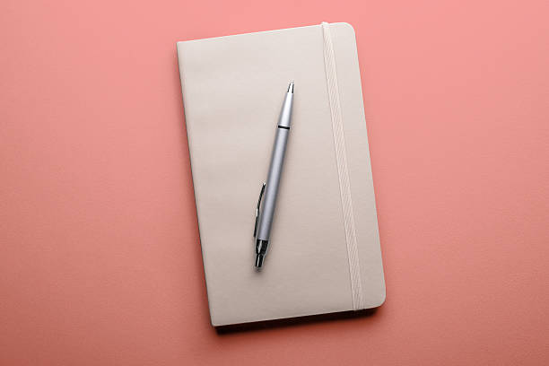 istock Old open book with fountain pen on pink background 543348112