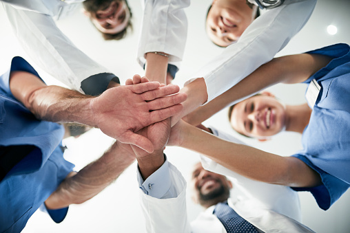 Shot of a diverse team of doctors joining their hands together in unity