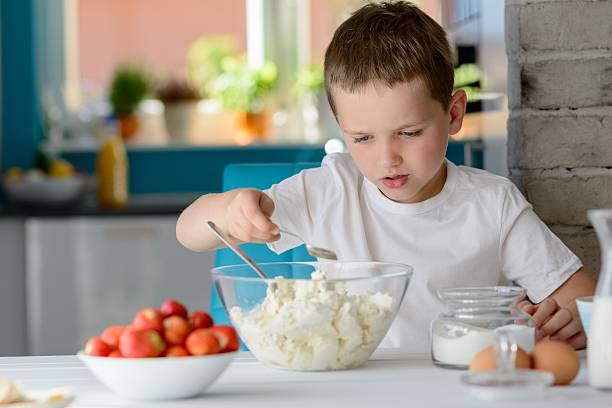 istock Child adding sugar to cottage cheese in a bowl. 543352778