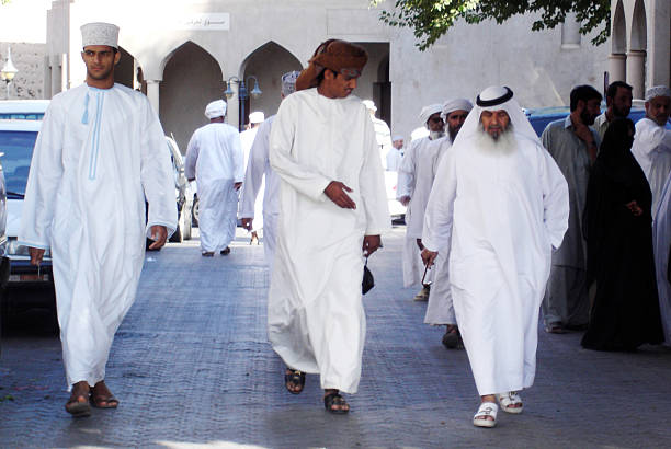 Nizwa, Oman - December 28, 2007: Omani men wear traditional Dishdasha clothing in Nizwa, Oman. It's an ankle-length garment commonly worn in Arab countries.