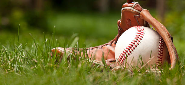 palla da baseball e guanto su erba verde - baseball field grass baseballs foto e immagini stock