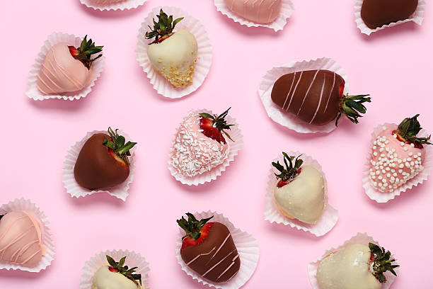 Strawberries covered in chocolate on a pink stock photo