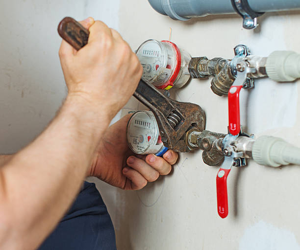 istock Male plumber fixing water meter with adjustable wrench. 543356806