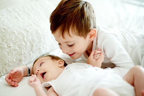 Shot of an adorable little boy bonding with his baby sister at home