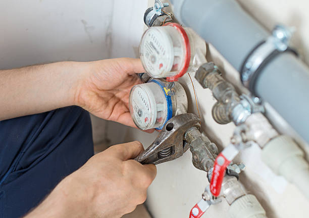 Male plumber fixing water meter with adjustable wrench. stock photo
