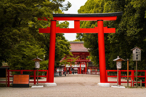 Kyoto, Japan - May 26, 2016: Trees surround the torii gate in Shimogamo Shrine in Kyoto, Japan. People can be seen upon closer inspection.
