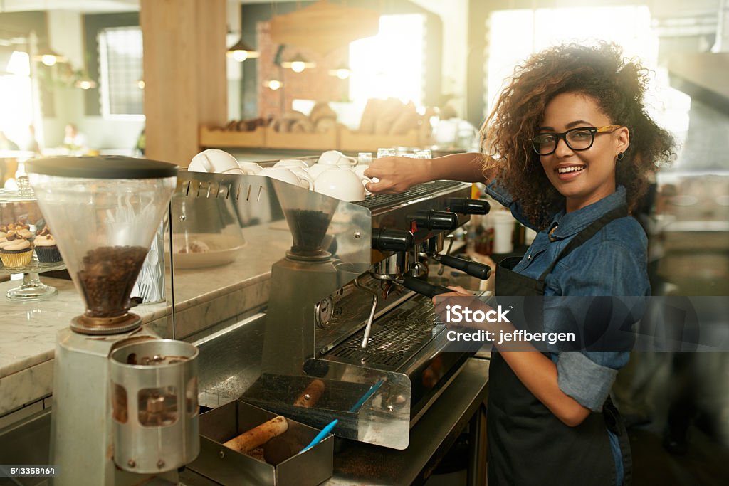 Skilled in the art of making coffee Portrait of a young woman preparing coffee at a cafe Barista Stock Photo