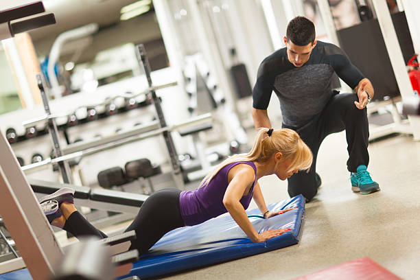istock Coach assisting young woman doing push-ups  at a gym. 543361306