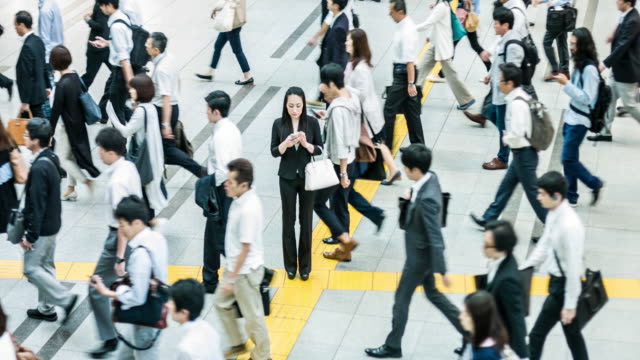 Japanese woman talking on the mobile phone surrounded by commuters