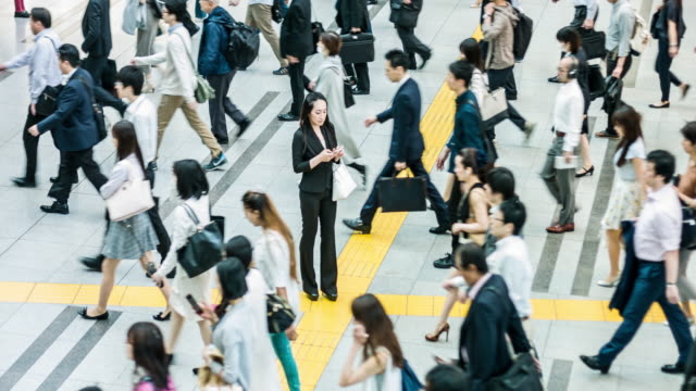 Japanese woman talking on the mobile phone surrounded by commuters