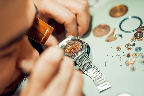 A watchmaker or repair man in action,viewing very closely a watch.