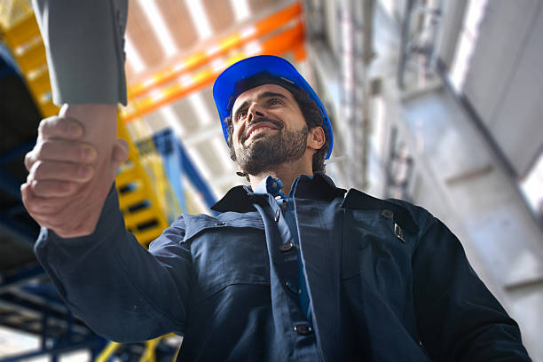 Men shaking hands in an industrial facility stock photo