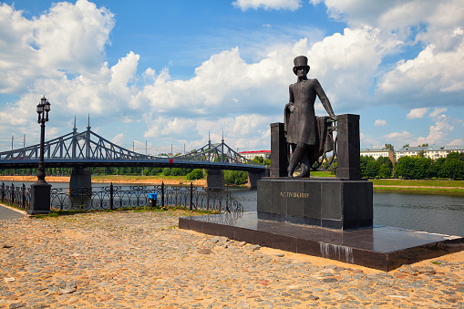 The monument to Alexander Pushkin in Tver, Russia. The old Volga bridge and the Volga river in the background