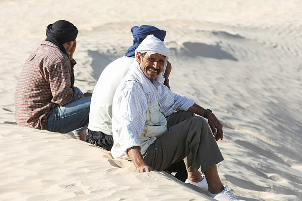 Bedouins in Sahara Douz, Kebili, Tunisia - September 17, 2012 :  Bedouins resting on the sand during the tourist tour on camels around the beginning of Sahara desert in Douz, Kebili, Tunisia. tunisia sahara douz stock pictures, royalty-free photos & images