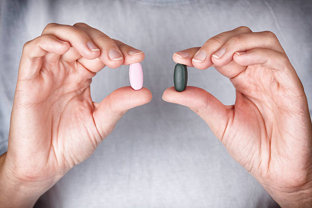 mujer sosteniendo pastillas de colores en sus manos - pink pill fotografías e imágenes de stock