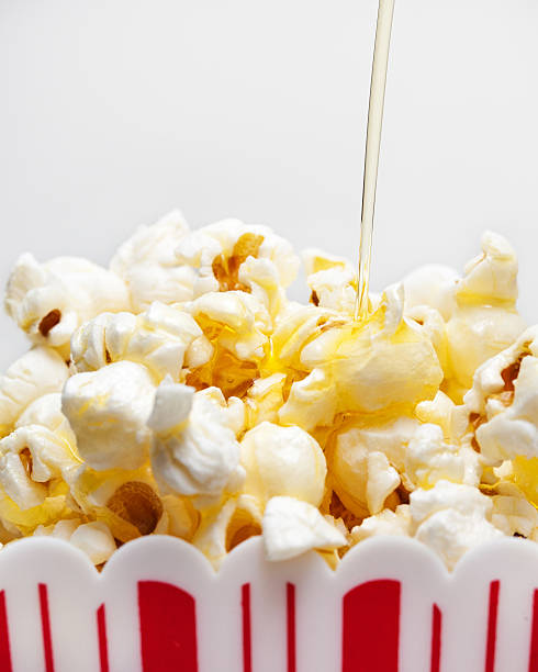 Butter Drizzling Over Popcorn Melted butter being poured over a bucket of fresh popcorn clarified butter stock pictures, royalty-free photos & images